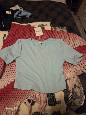 Ljusblå topp från ONLY - Snygg ljusblå topp från ONLY med korta ärmar och rund hals. Modellen är croppad och har en enkel, stilren design som passar perfekt till jeans eller kjol. Tillverkad i mjuk bomull för en bekväm känsla.