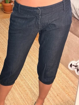 Mörkblå capris med resår🌸 - Snygga mörkblå linnebyxor i caprimodell med resår vid benslut och knappgylf. Byxorna har fickor fram och dekorficka bak. Perfekta för en avslappnad och trendig look. Materialet är lätt och luftigt linneblandning.