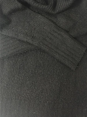 Svart stickad polotröja - En klassisk svart stickad polotröja med ribbade muddar och hög krage. Perfekt för lager på lager och enkel att matcha med olika stilar. Materialet känns mjukt och bekvämt mot huden.