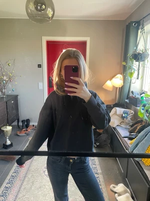 Svart hoodie med avslappnad passform - En enkel svart hoodie med luva och långa ärmar. Hoodien har en avslappnad passform och saknar synliga tryck eller loggor. Perfekt för en chill och casual stil. Tillverkad i mjukt material som känns skönt mot huden.