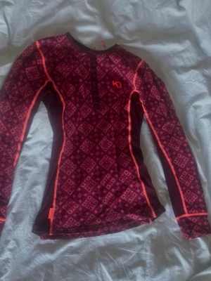 Underställsset från Kari Traa vinröd/rosa - Säljer ett underställsset från Kari Traa i vinrött med rosa mönster och kontrastsömmar. Setet består av långärmad tröja och byxor. Det är ganska tajt passform men perfekt när man åker skidor/snowboard eller bara är ute i snön. 