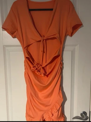 klänning med snörning & cut-out - Wow-klänning i stark orange färg som verkligen sticker ut! Kort modell med djup v-ringning, snygg snörning framtill och trendig cut-out under bysten. Volangdetalj nertill och korta ärmar Perfekt till fest, semester eller när du vill vara kvällens blickfång 🔥(har bh under, ifrån shein) 