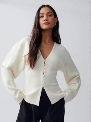 Gina tricot kofta  - Stilren krämvit kofta med v-ringning och dekorativa knappar framtill. Koftan har lång ärm och en mjuk, något lös passform. Perfekt att matcha med både jeans och kjol för en trendig look.