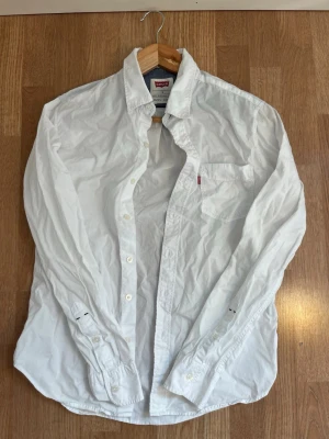 Vit skjorta från Levi's i bomull - Klassisk vit skjorta från Levi's i bomull. Behöver endast en strykning så är den så gott som ny! Storlek S med snygg passform. Tveka inte på att höra av dig ifall du undrar något!✨