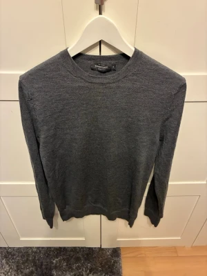 Mörkgrå merino woll - En enkel och stilren mörkgrå merino ull tröja från Dressmann. Tröjan har rund halsringning, långa ärmar och ribbade muddar vid ärmslut och nederkant. Passar dig som gillar en clean och klassisk look.