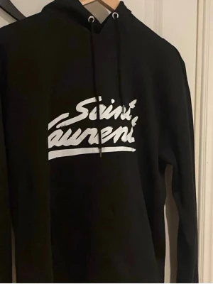 Svart Saint Laurent hoodie - Säljer min Saint Laurent hoodie då jag inte gillade passformen så försöker få ut lite pengar av den ist. Perfekt till våren väldigt stilren och Clean.                        Kom dm för mer frågor 📬💫
