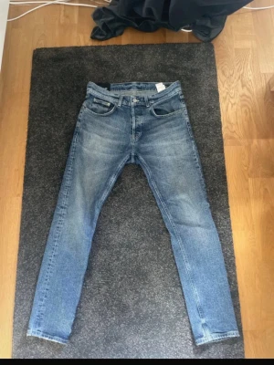 dondup jeans - Säljer ett par klassiska blå jeans från dondup  med smal passform och fem fickor. Jeansen har en snygg tvättad look och är gjorda i denim. Perfekta för dig som gillar en enkel och stilren stil.