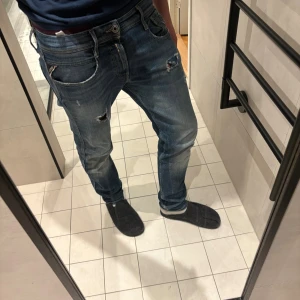 Blå slitna jeans med hål Replay - Säljer ett par blå jeans med slitningar och hål på låret och knät. Jeansen har en klassisk femficksmodell. 