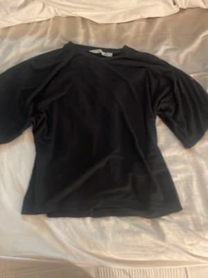 Svart insydd waist tshirt  - En enkel och stilren svart topp med insyd waist