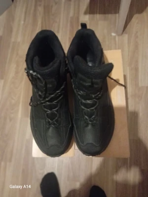 Svarta moon boots med snörning - Säljer ett par svarta moon boots med högt skaft och snörning framtill. De har en vadderad insida och robust yttersula, perfekta för kalla vinterdagar. Materialet är syntet med textilfoder för extra värme och komfort. Stilsäkra och funktionella för vintern.