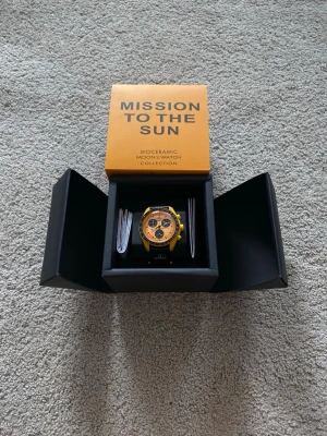 Omega x Swatch Mission to the Sun - Säljer en Omega x Swatch Mission to the Sun från Bioceramic MoonSwatch Collection. Klockan har en gul boett, orange urtavla och svarta detaljer med tachymeter. Snygg och unik design som sticker ut på handleden. Levereras i originalbox.