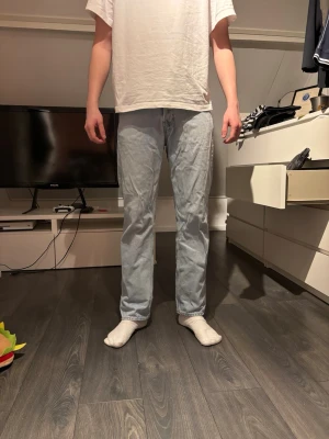 Ljusblå raka jeans - Säljer ett par ljusblå jeans med rak passform och klassisk femficksdesign. Jeansen har normal midja och är tillverkade i ett mjukt denimtyg som ger en avslappnad look. Perfekta för dig som gillar en enkel och stilren stil.