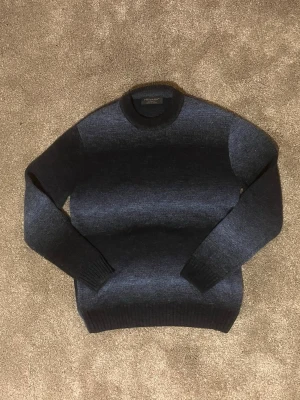 Unik blå stickad tröja - Otroligt unik blå tröja med lite olika nyanser vilket gör att den ser lite ”washed” ut. Tröjan är gjord av ull och är i bra skick. Den har inte några defekter. Tröjan är igentligen i storlek XS men passar mer S/M.  Skick: 9,5/10    Storlek: S/M