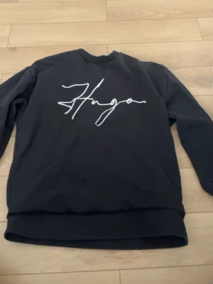 Svart sweatshirt från Hugo - Jag säljer en äkta hugo boss tröja från room 1006, knappt använd och den är liten nu på mig den är perfekt för dig som vill ha något unikt och fint.