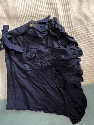 Mörkblått nattlinne med volangkant - Mörkblå shorts från Polarn o. Pyret med volangkant och knytband i midjan. Tillverkade i mjuk bomull för en bekväm känsla. Perfekta för sommardagar när du vill ha något enkelt men ändå snyggt.