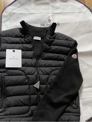 Moncler Cardigan  - ⚪️Nu säljs Moncler Cardigan i fräscht skick,⚪️     Perfekt för att hålla dig varm med stil, dessutom sval till den Svenska Sommaren & våren, Storlek M. Knappt till inget tecken på användning. Moncler Dustbag & kort finns självklart. Tveka inte att skriva vid minsta fundering. 🤝😊