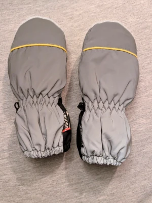 Grå och svarta vintervantar från Didriksons - Snygga och praktiska grå reflex vantar från Didriksons med svart handflata och elastisk mudd. 