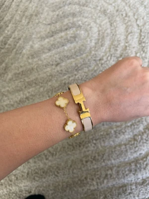 H armband med fyrklöver - Säljer ett elegant armband i guldton med vita pärlliknande fyrklöverhängen och tunn kedja. Armbandet har fina detaljer och ger en lyxig känsla, perfekt för dig som gillar stilrena accessoarer med det lilla extra. Både armbanden för 599 fyrklöver 17+5cm andra armbandet är 16cm kolla gärna mina andra smycke och annat.