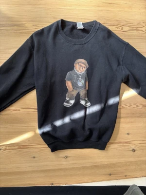 Svart sweatshirt från polo Ralph lauren  - Svart sweatshirt med tryck av Björn figur på framsidan. Från Polo Ralph Lauren, storlek M