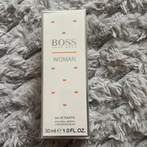 Hugo Boss Woman Eau de Toilette 30ml - Hugo Boss Woman Eau de Toilette är en fräsch och elegant parfym i en stilren vit förpackning med silverdetaljer. Flaskan rymmer 30 ml och är perfekt att ha med i väskan. Doften är feminin och modern, och passar dig som gillar klassiska men ändå ungdomliga parfymer.