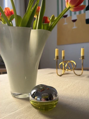 DKNY Be Delicious parfym - Fräsch parfym från DKNY, Be Delicious, i en rund, äppelliknande flaska med silverfärgat lock och grön botten. Flaskan är tillverkad i glas och metall och har en modern, ungdomlig design. 