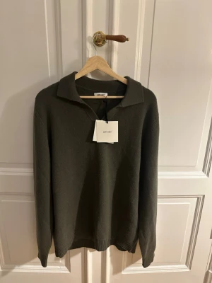 Soft Goat - Mysig mörkgrön stickad tröja från Soft Goat i mjuk kashmir. Tröjan har krage, lång ärm och ribbade muddar vid ärmslut och nederkant. Perfekt för dig som gillar stilrena och bekväma plagg.