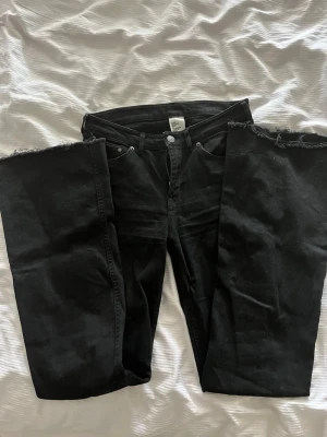 Svarta flare jeans från H&M - Säljer ett par svarta jeans från H&M.Jeansen är mid waist.En av bakfickorna har en grön/gul söm. Sömmen är sydd i ett korsat mönster(bild finns).