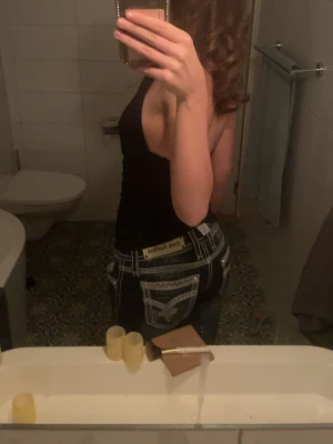 Mörkblå Rock Revival jeans - Säljer ett par mörkblå jeans från A2vintage som har vita kontrastsömmar och snygga  detaljerade jackfickor . Klassisk låg midja och raka ben. Snygga detaljer och ikonisk etikett bak i midjan. Nypris 1200