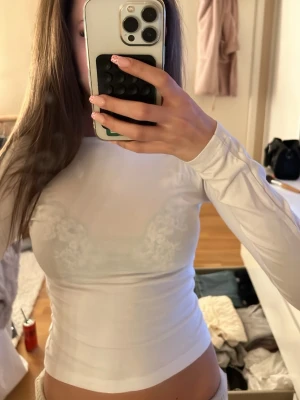 Vit långärmad med öppen rygg - Säljer en vit långärmad topp med tight passform och rund halsringning. Toppen har en  öppen rygg och kan även användas åt andra hållet om man vill