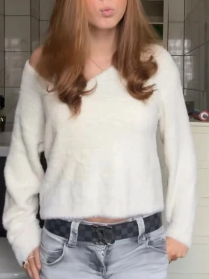 Vit off shoulder stickad tröja - Mysig vit stickad tröja med off shoulder-design och långa ärmar. Tröjan har en lös passform och är tillverkad i ett mjukt material som ger en avslappnad look. Perfekt för dig som gillar en enkel men trendig stil.