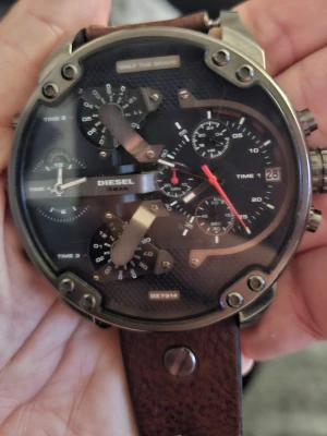 Diesel DZ7314 Big Daddy Äkta - Stor och maffig klocka från Diesel, modell DZ7314. Klockan har svart urtavla med flera tidzoner, datumvisning och detaljer i silver. Boetten är robust med industriell känsla och armbandet är i brunt skinn. Perfekt för dig som gillar statement-accessoarer. Kvitto finns 