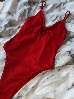 Röd body - Snygg röd body med smala axelband, perfekt för fest😛sätter sig tight men är stretchig i tyget. Har inte använt den särskilt mycket. Kontakta för fler bilder om du vill se något specifikt, svarar så snabbt jag kan!