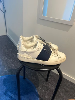 Valentino vita sneakers med blå detalj - Äkta Valentinos i storlek 41. Bra skick. Har en skavank vid höger stortå där sulan lossar (se bild). Kvitto finns samt kartong och skopåsar vilket är unikt. Fråga om du vill ha fler bilder. Tveka inte. Kvitto, kartong och skopåsarna medföljer såklart😊 kan gå ner i pris vid snabb affär.