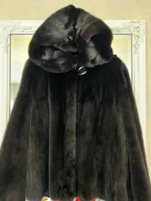 Svart diamant päls cape med huva - Säljer en elegant i blackdiamant färg cape i päls med stor huva och knäppning framtill. Capen har en lyxig känsla och ett klassiskt snitt som ger en tidlös look. Perfekt för dig som vill sticka ut med en unik ytterjacka. I storlek S M 