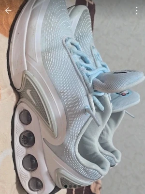 Nike Air Max vita sneakers - Snygga Nike Air Max sneakers i vitt och ljusblått med tydliga Air Max-bubblor i sulan. Ovandelen är i mesh och syntetmaterial för bra andningsförmåga och komfort. Klassisk Nike-logga på sidan och Air Max-detalj på hälen. Perfekta för dig som gillar sportig stil.