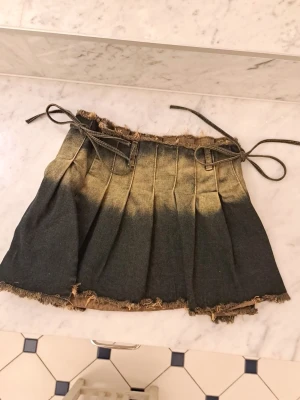 Justerbar jeans kjol med snörning - Mörkblå mini jeans kjol med beiga detaljer i mitten💕 kjolen har 2 snören på varje sida som man knyter ihop kjolen med! (alltså är den justerbar) i storlek XS men passar mig som har storlek S. knappast använd!