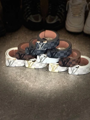 Louis Vuitton rutiga bälten - Säljer flera Louis Vuitton bälten i klassiskt rutigt mönster. Finns i färgerna svart, brunt och vitt med olika LV-spännen i silver och guld. Bältena har en stilren design och är tillverkade i konstläder med metallspänne. Perfekt accessoar för att lyfta din outfit.              Alla bälten finns i min profil. In och beställ.