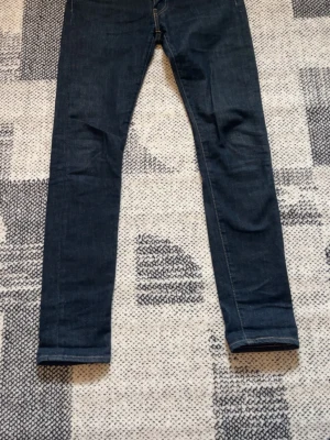 Mörkblå Levi’s jeans - Snygga mörkblå slimfit jeans med klassisk femficksdesign och kontrastsömmar. Jeansen har smal passform och är tillverkade i ett stretchigt denim-material som sitter tight och bekvämt. Perfekta för dig som gillar en modern och stilren look. W30 l32