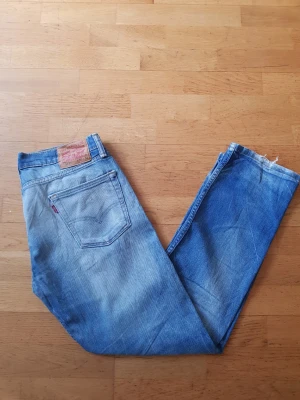 Levi's 513 ljusblå jeans - Säljer ett par klassiska Levi's 513 jeans i ljusblå tvätt. Modellen har rak passform och fem fickor, med den ikoniska röda Levi's-lappen på bakfickan och läderpatch i midjan. Perfekta för en avslappnad och tidlös stil.