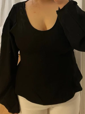 Svart blus med puffärmar - Snygg svart blus med djup rundringning och långa puffärmar. Figurnära passform som markerar midjan och ger en elegant siluett. Använd 1 gång.                                               Leverans med Instabox eller mötesplats. 