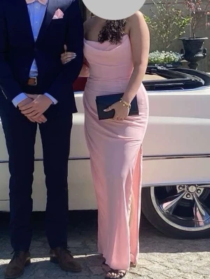 Ljusrosa långklänning House of CB - Säljer en elegant ljusrosa långklänning från House of CB med slits på sidan och ärmlös design. Klänningen har en draperad överdel och figurnära passning som framhäver siluetten. Perfekt för bal eller bröllop. Storlek M/38. Köptes för 3200 ungefär! Använd en gång.