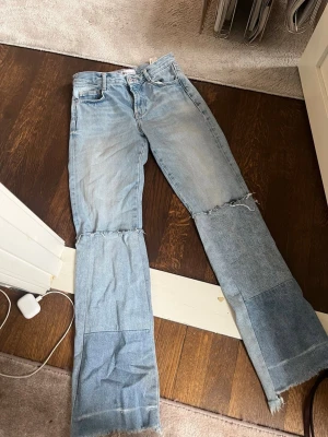 Zara jeans  - Unika ljusblå jeans från Zara. fransiga kanter vid knä och benslut. Rak passform och klassisk femficksmodell. Perfekta för dig som gillar en trendig och avslappnad stil.