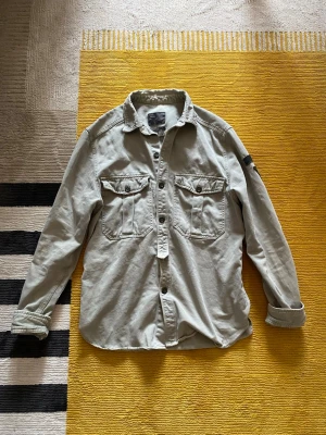 Beige manchester overshirt - Säljer en beige overshirt från Jack & Jones i mjuk manchester. Skjortan har två stora bröstfickor med knappar, klassisk krage och långa ärmar. Perfekt lager-på-lager-plagg med avslappnad passform och snygga detaljer. Sitter som S men längden som M
