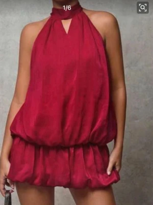 Röd halterneck klänning med shorts under  - Trendig röd klänning med halterneck. Lös passform med resår i midjan och korta ben. Tillverkad i ett lätt, flowy tyg som ger en snygg siluett. Perfekt för dig som vill sticka ut med en färgstark och modern look.