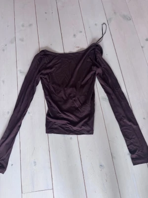 Brun långärmad topp från Gina - Trendig brun långärmad topp från Gina tricot med rygglös design och smal passform. Tillverkad i mjukt material som sitter snyggt på kroppen. Perfekt för dig som vill ha en unik och stilren look.