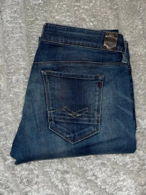 Replay jeans  - Blåa jeans från Replay med kontrast mönster. Jeansen har en Skötn passform med en låg midja. Midja 41cm, längd 106cm.  JAG SKICKAR EJ FLER BILDER NÄR JAG BÄR JEANSEN! för bättre inblick i passformen rekommenderar jag att googla på modellnamnet. För storleksguide kolla måtten noggrant då jeansen alltid kan vara uppsydda heller krympta och jag ej tar emot returer :) s6,5