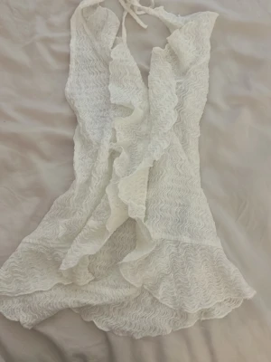 Vit fest topp med klassiga detaljer  - Jag säljer en vit fest topp som aldrig används. Den är en snörad halterneck topp med volang detalj där fram och öppen rygg.