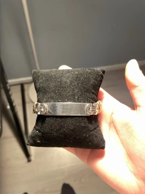 Stilrent armband i silver och guld - Säljer ett snyggt armband i metall med både silver- och guldfärgade detaljer. Armbandet har en platt, blank mittdel och coola länkar med guldfärgade ringar. Perfekt accessoar för dig som gillar en modern och stilren look.