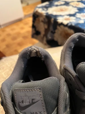 Grå Nike Air Max sneakers - Snygga grå Nike Air Max sneakers med klassisk siluett. Skorna har ovandel i mesh och syntetmaterial, samt tydlig Air Max-dämpning i sulan. Gråa skosnören och detaljer, samt diskret Nike-logga på plösen. Perfekta för dig som gillar streetwear och sportig stil.