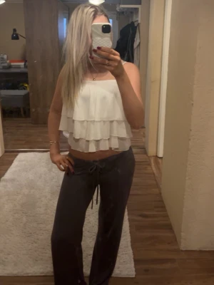 Vit volangig crop top - Säljer en vit crop top med flera lager volanger. Toppen har tunna axelband och en luftig, flowy passform som ger en romantisk vibe. Perfekt för sommardagar eller när du vill ha en lätt och söt look.